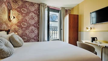 Camera d'albergo con un letto grande, una scrivania con sedia, una TV a schermo piatto e vista su un balcone.