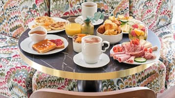 Une table de petit-déjeuner avec divers aliments, une tasse de café et un verre de jus d’orange.