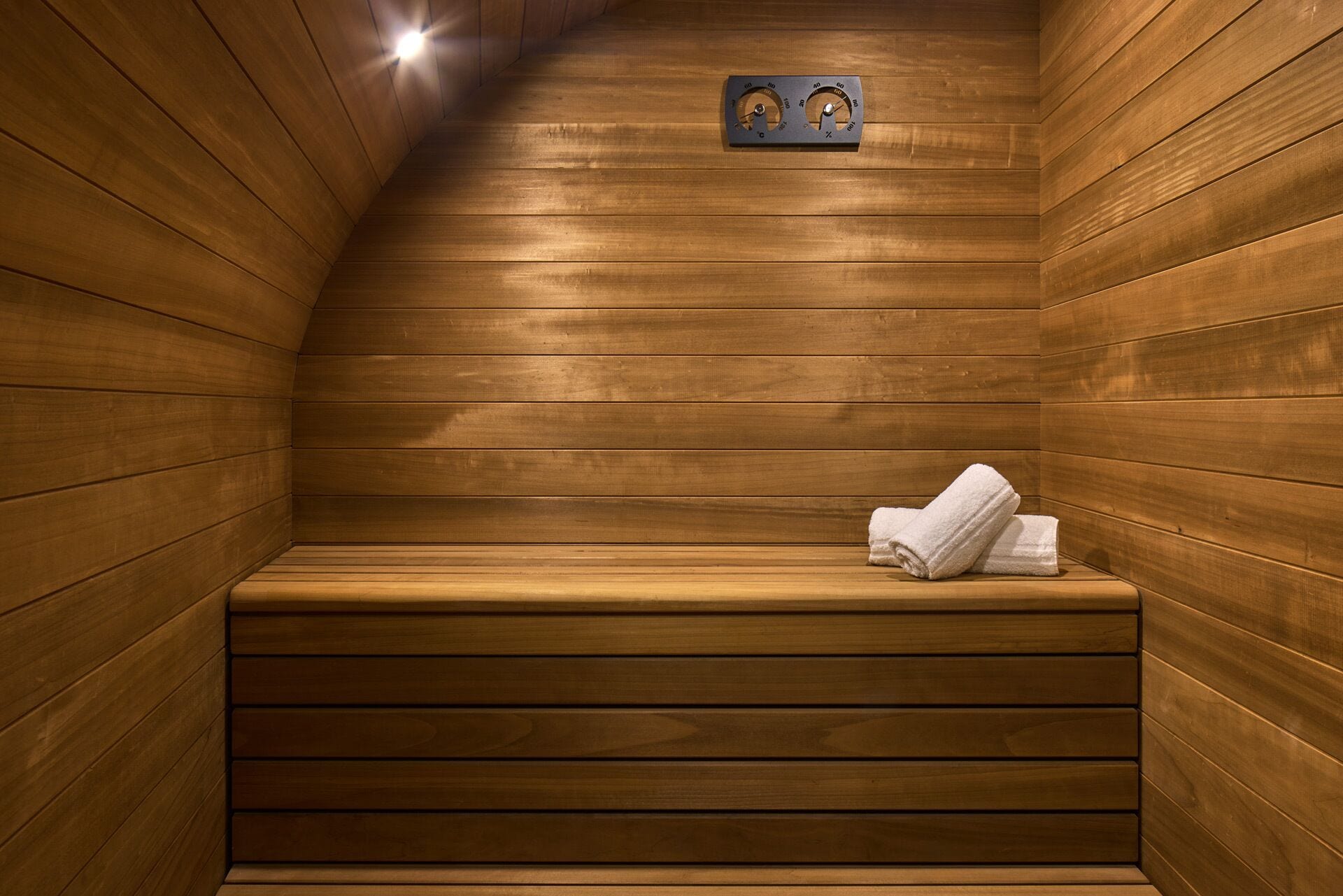 A wooden sauna with benches and a towel rack.