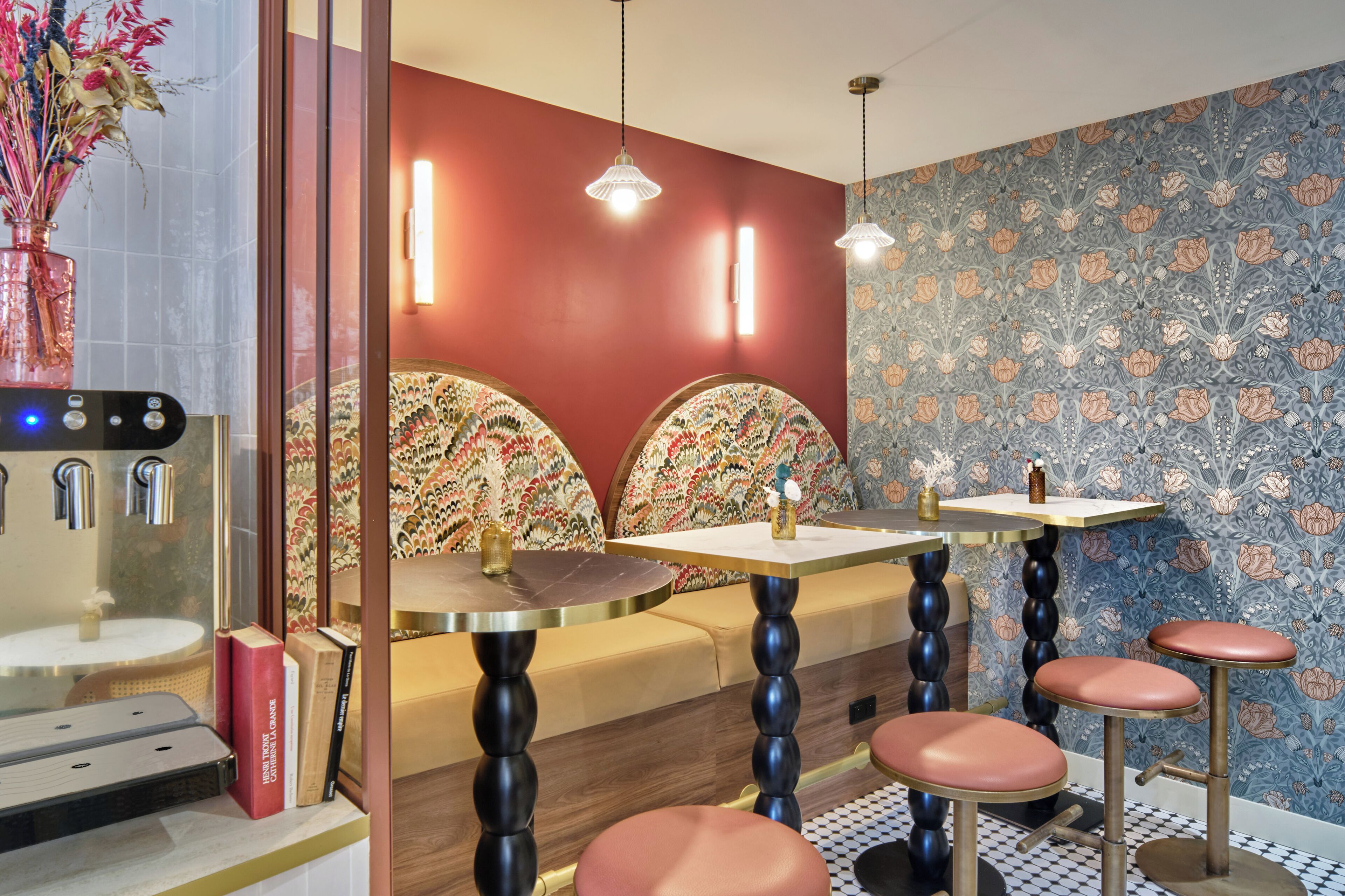 Una camera d'albergo moderna con un divano, due sgabelli da bar, un tavolino e un vaso decorativo.