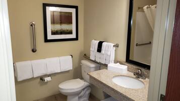 A bathroom with a toilet, sink, and a framed picture on the wall.