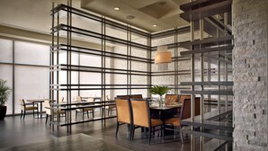 A modern dining area with a central table, chairs, and a hanging light fixture.