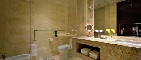 A modern bathroom with a glass shower enclosure, a bidet, a vanity with a mirror, and a sink.