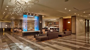 A modern lobby with a bar area, seating, and a decorative ceiling light fixture.