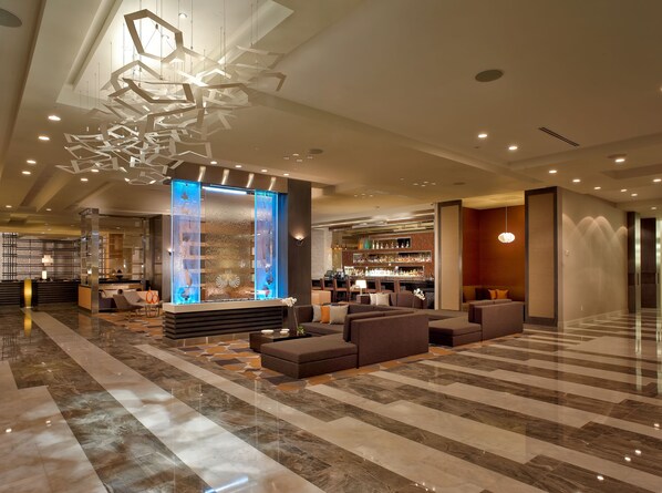 A modern lobby with a bar area, seating, and a decorative ceiling light fixture. - EB Hotel Miami (Miami Springs)