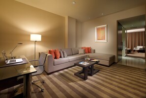 A modern living room with a sofa, coffee table, and a desk with a laptop.