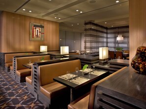 A modern restaurant with booth seating, tables with menus, and ambient lighting. - EB Hotel Miami (Miami Springs)