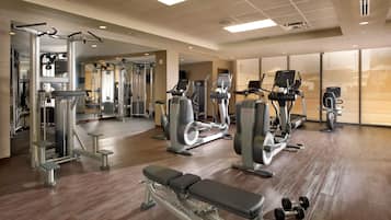 Un gimnasio con equipo de ejercicio variado, incluyendo cintas de correr, elípticas y bancos de pesas.