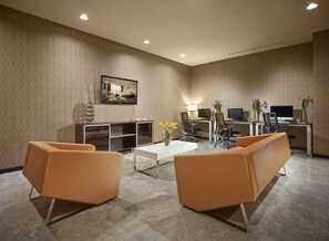 A modern conference room with a large table, two sofas, and a television mounted on the wall.