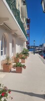 Un edificio frente al agua con balcones, plantas en macetas y una vista despejada del puerto deportivo.