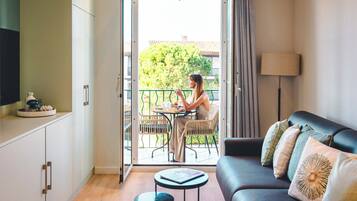 A modern living room with a sofa, a small table, and a balcony area with a table and chairs.