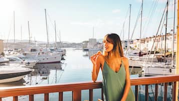 Eine Frau steht auf einem Balkon mit Blick auf eine Marina und Boote.