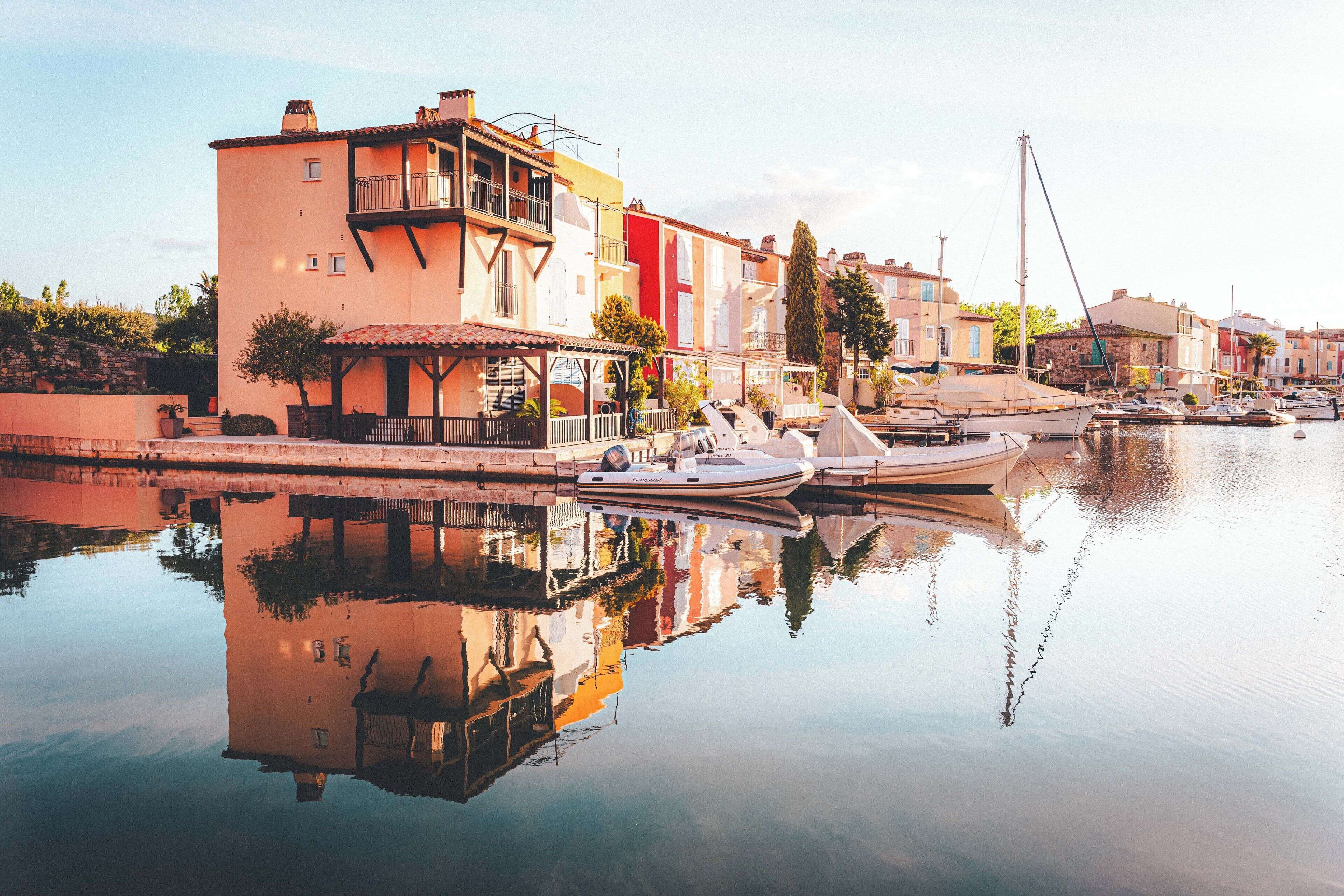 Propiedad frente al agua con un muelle para barcos, edificios reflejados y una superficie acuática tranquila.