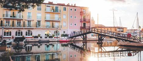 A waterfront building with balconies, a bridge, and boats.