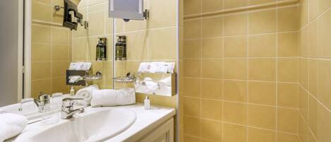 A bathroom with a white sink, mirror, and shower area.