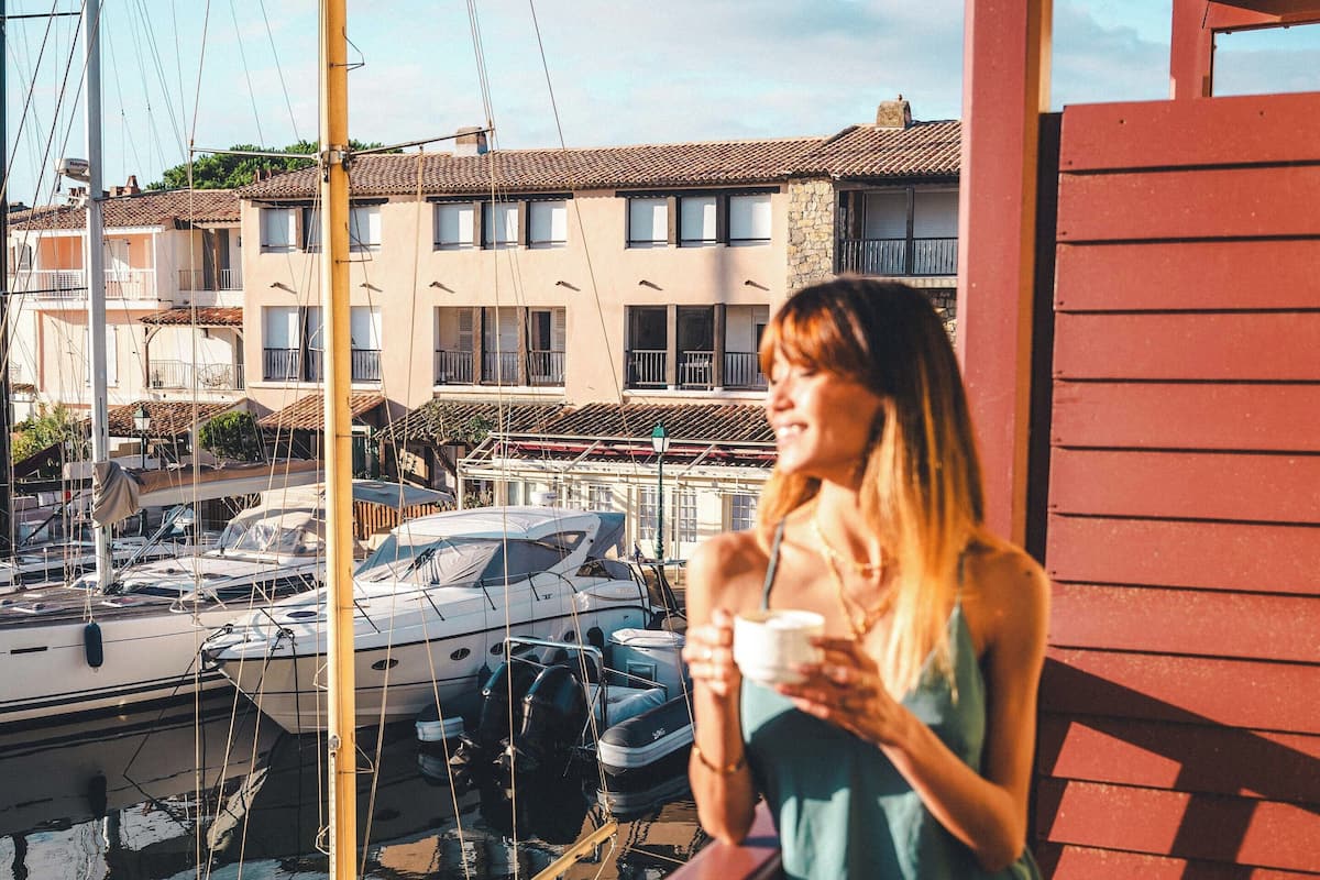 A balcony with a view of a marina, a dining table with breakfast items, and a cityscape in the background.