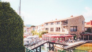 A dining table with breakfast items and a view of a riverside town. -  Le Suffren Hotel, Golfe de Saint-Tropez (Grimaud)