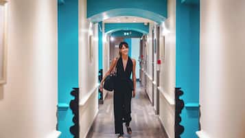 Un couloir d’hôtel aux couleurs turquoise, une femme qui marche, et un design moderne.