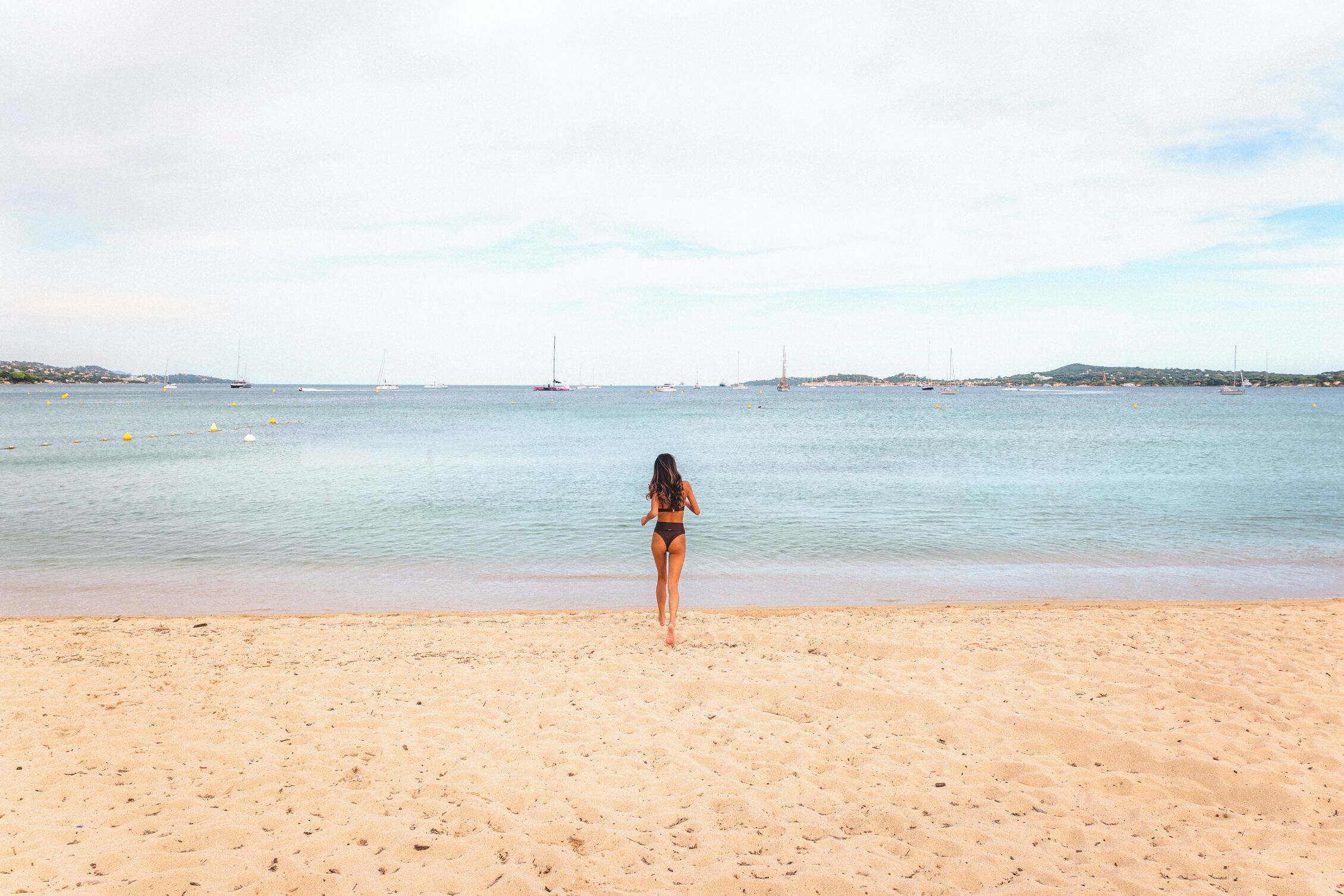 A beach with a person walking towards the water.