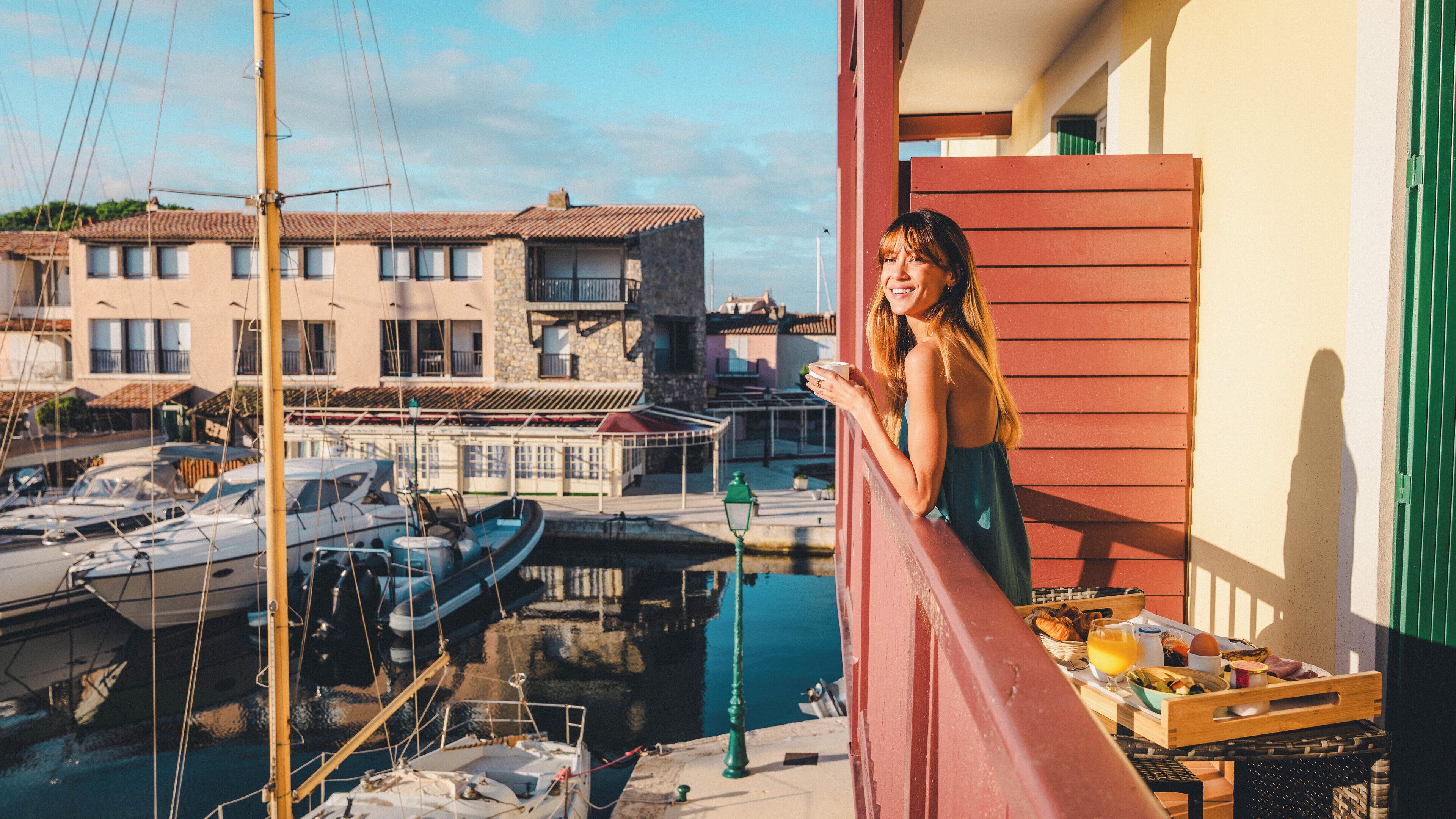 A balcony with a view of a marina, boats, and buildings in the background.
