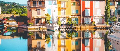 A waterfront building with a reflection in the water, featuring balconies and a clear sky.