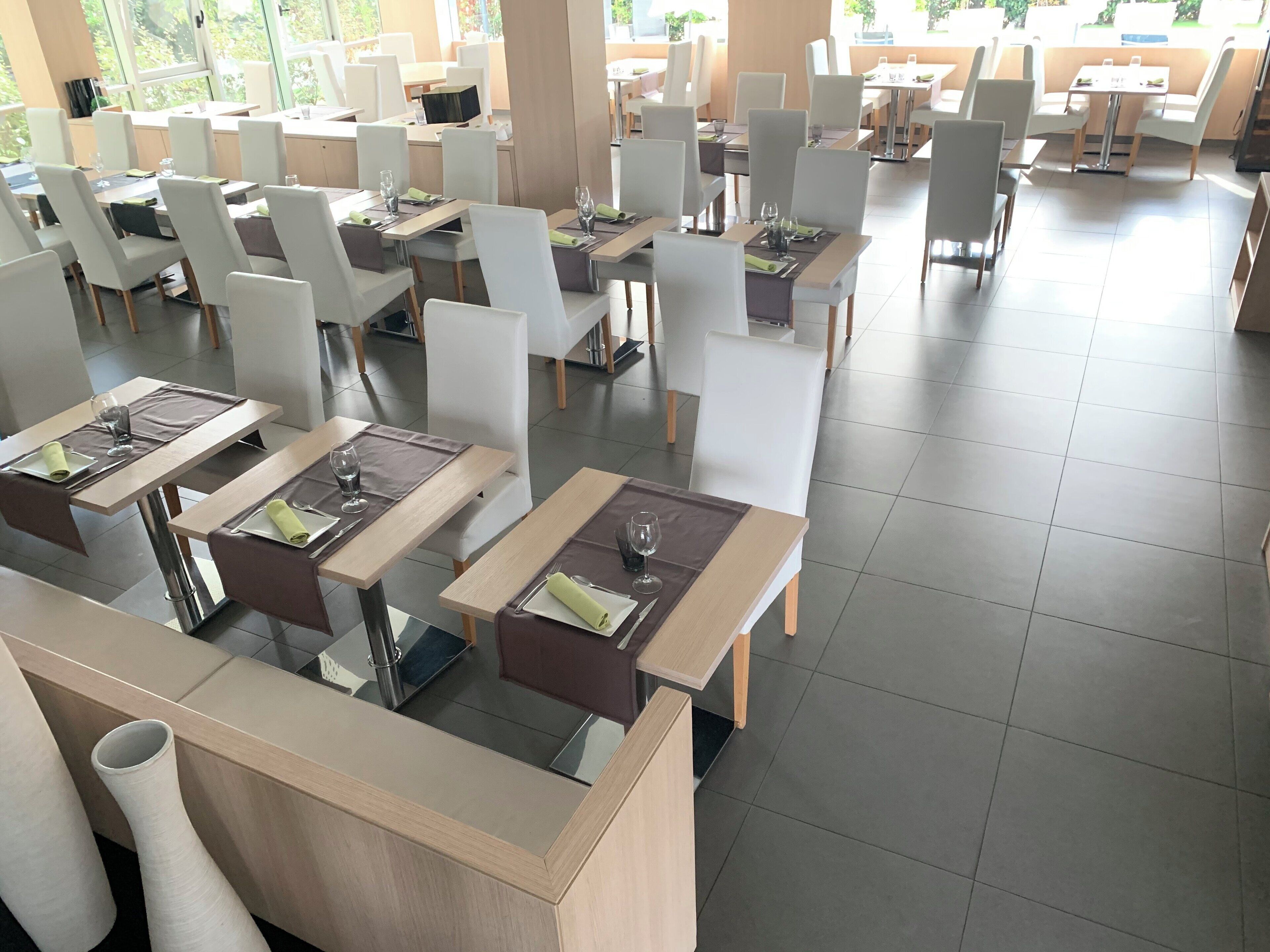 Un restaurante espacioso con varias mesas y sillas, dispuesto en una decoración moderna.