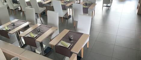 Un restaurante espacioso con varias mesas y sillas, dispuesto en una decoración moderna.