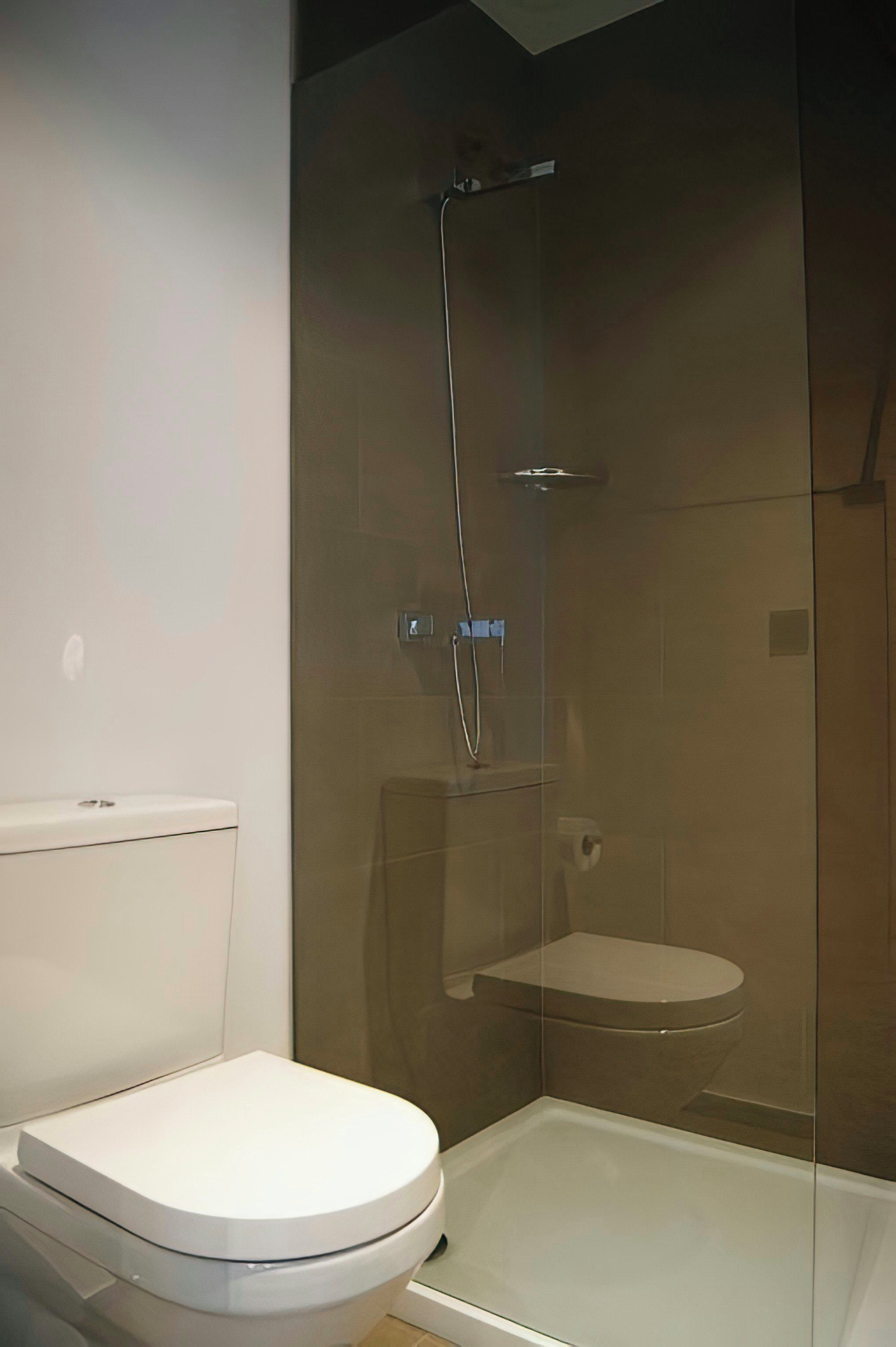 Une salle de bain comprenant des toilettes, une cabine de douche en verre et un bidet.