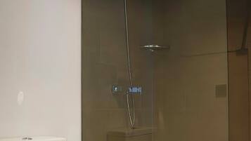 Une salle de bain comprenant des toilettes, une cabine de douche en verre et un bidet.