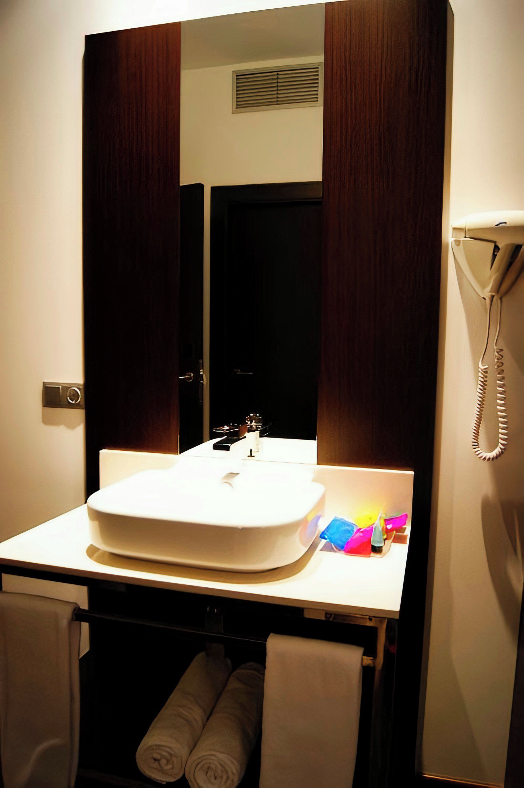 A bathroom with a white sink, a mirror, a telephone, and towels.