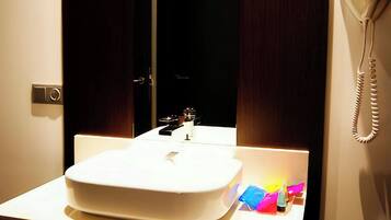 A bathroom with a white sink, a mirror, a telephone, and towels.