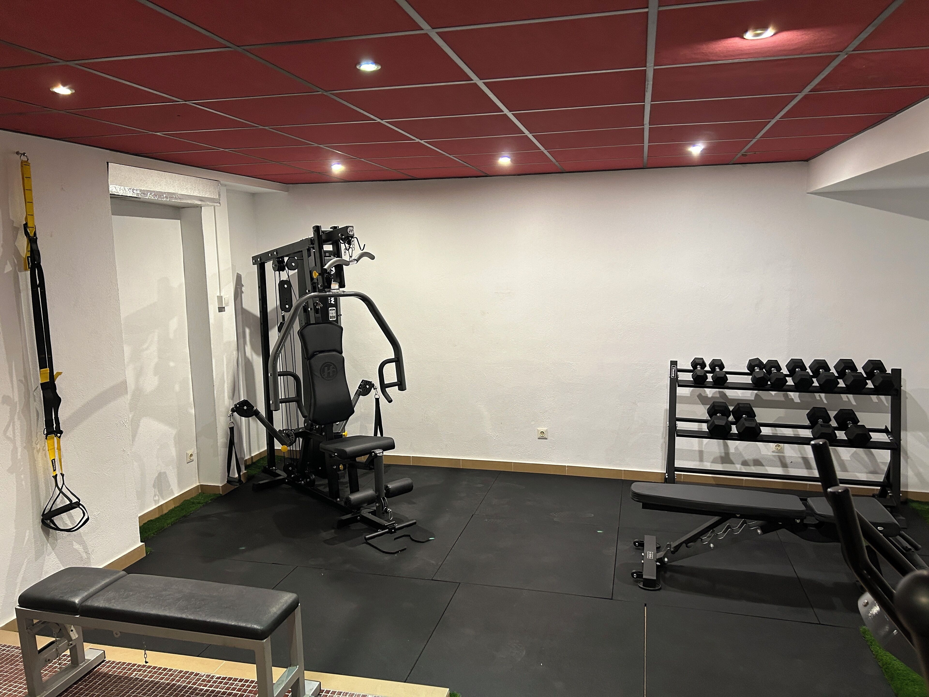 Une salle de sport équipée d’un banc, d’un support à poids et d’autres appareils d’exercice.