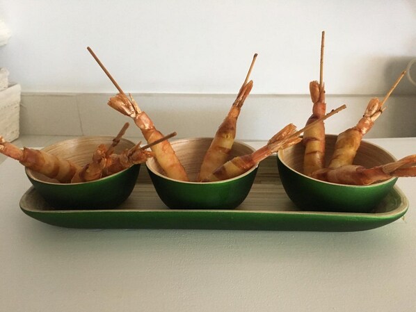 Tres boles verdes sobre una bandeja con camarones cocidos.