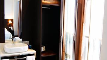 Een moderne badkamer met een wastafel, spiegel en inloopkast.