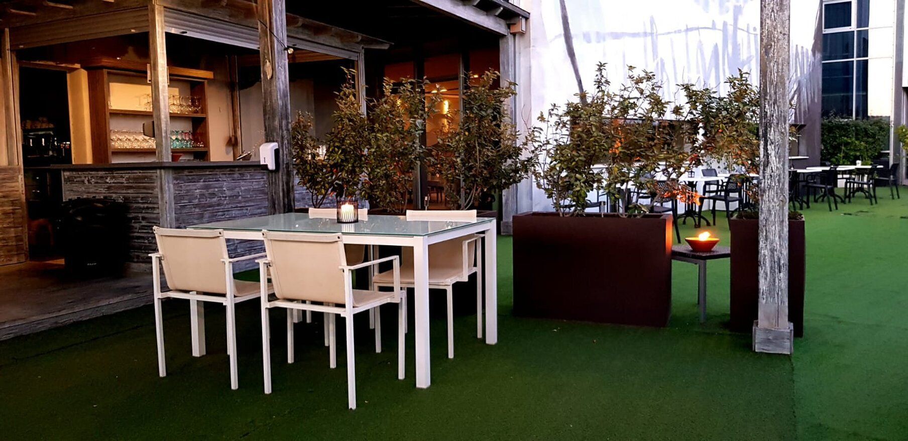 An outdoor seating area with a table and chairs, a small plant, and a candle on a table.
