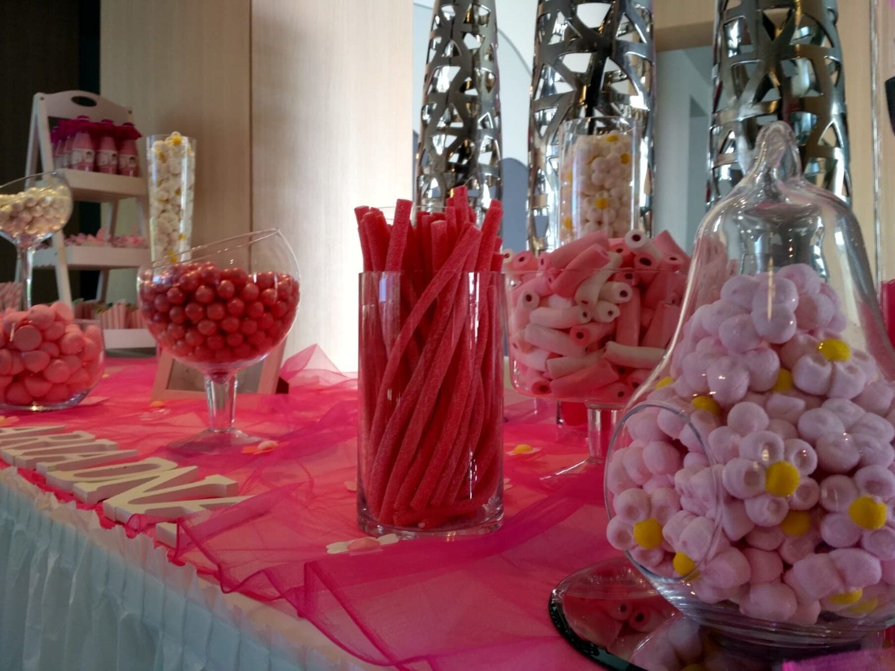 A table with various candy items in clear glass containers.