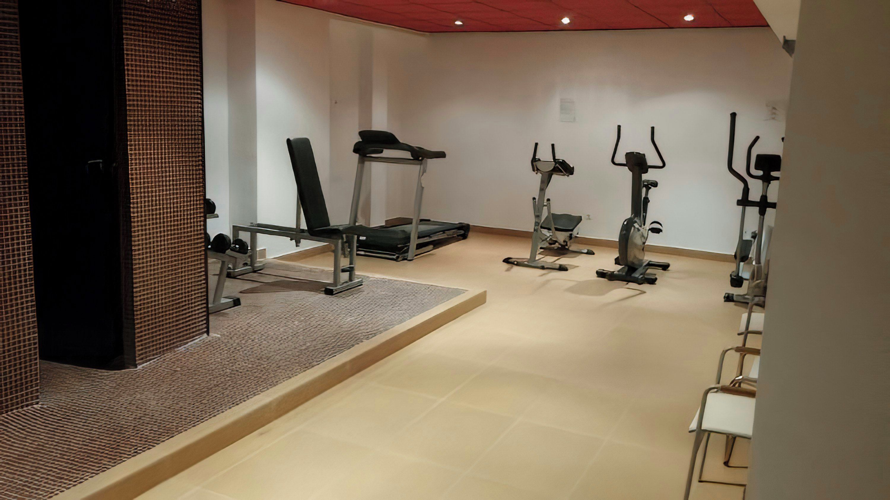 Academia com diversos equipamentos de exercícios, incluindo esteira, elíptico e bicicleta ergométrica.