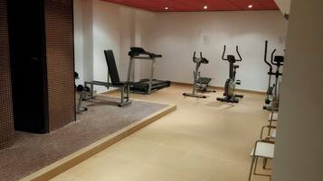 Academia com diversos equipamentos de exercícios, incluindo esteira, elíptico e bicicleta ergométrica.