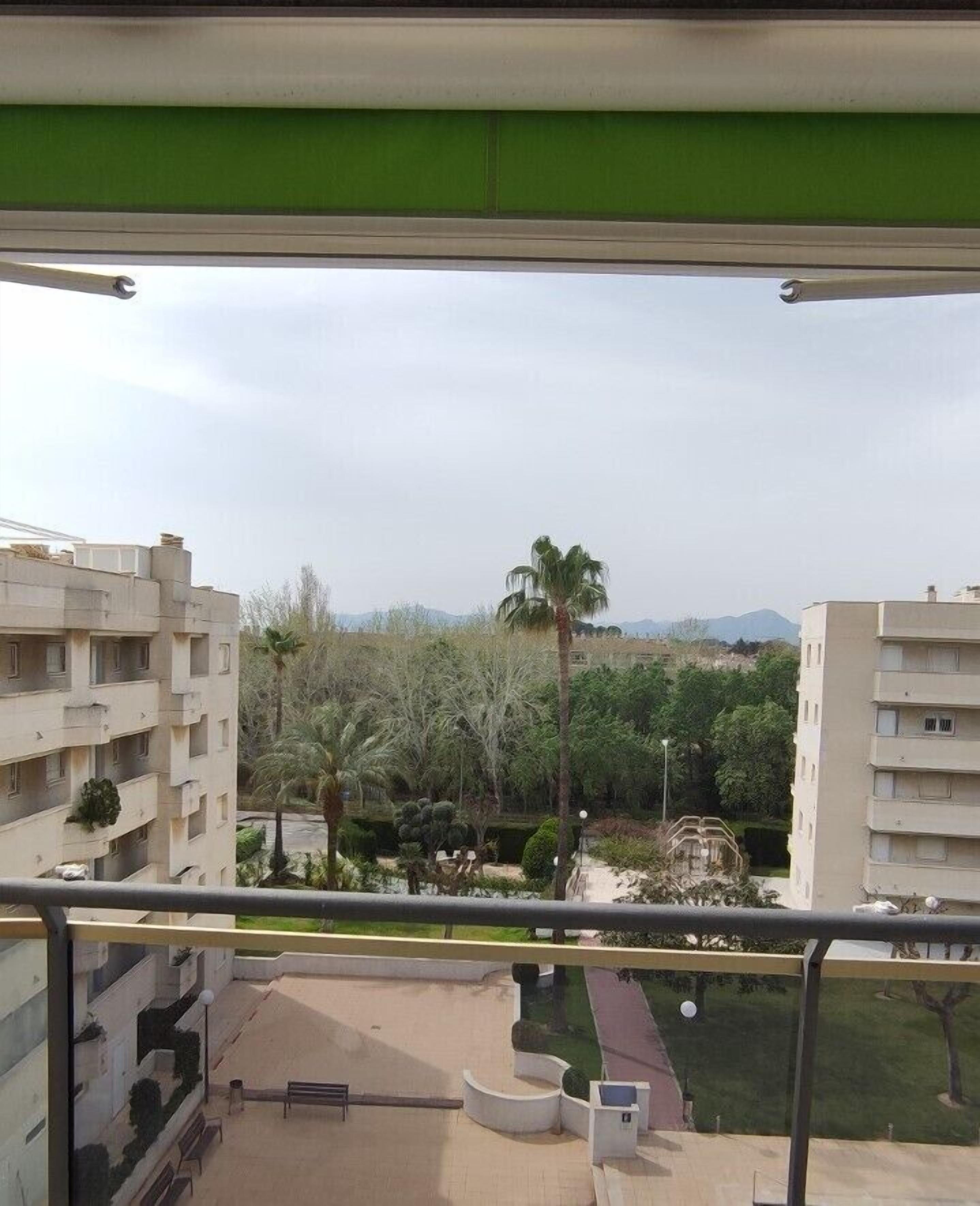 A balcony with a view of a residential area, including buildings and greenery.