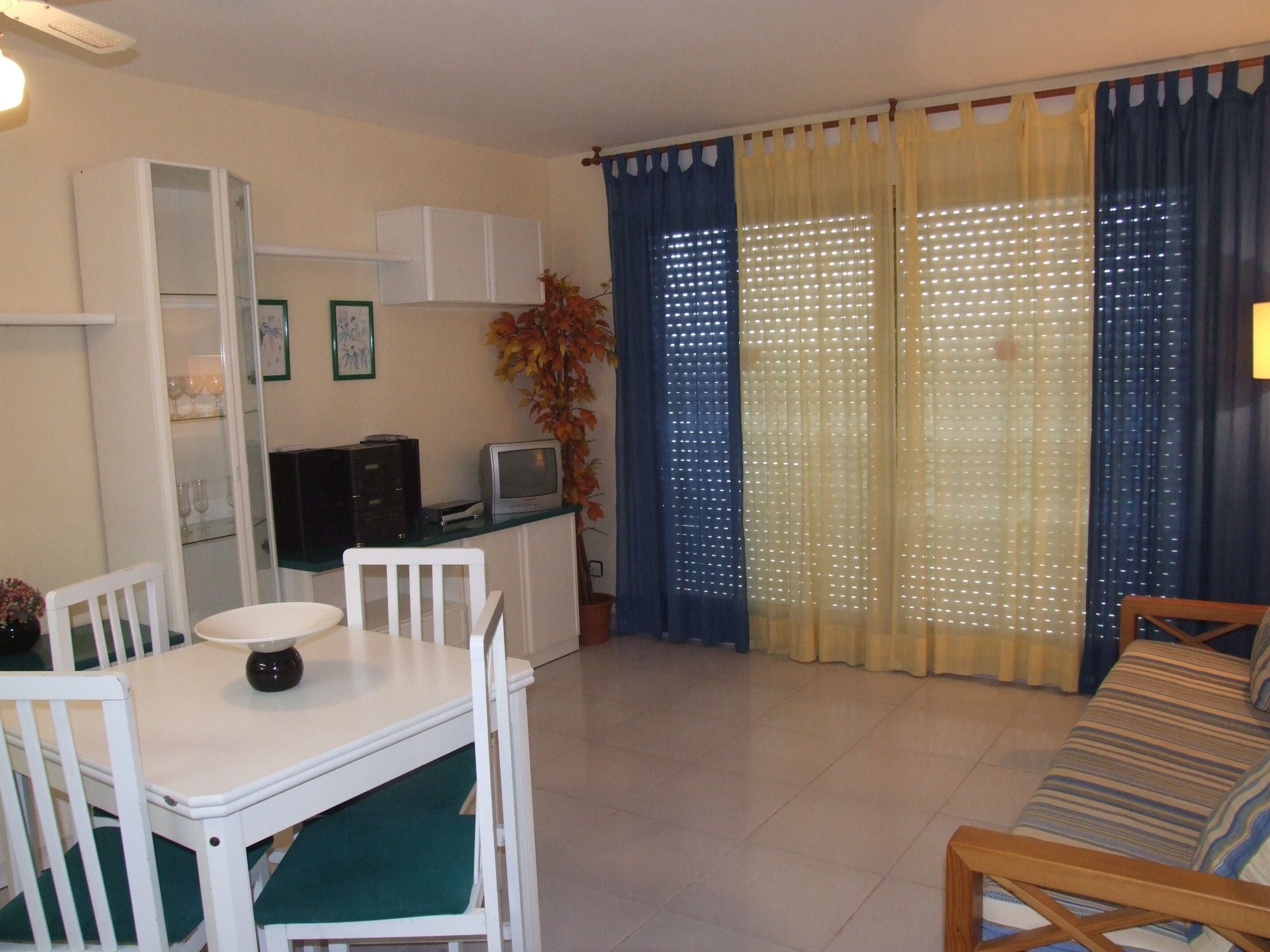A living room with a dining table, chairs, a sofa, a TV, and a cabinet.
