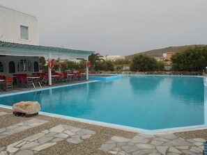 Piscina con zona de estar cubierta y suelo de piedra.