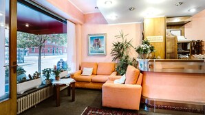 Eine Hotelhalle mit einer Couch, einem Couchtisch, einer Pflanze und Blick auf die Straße.