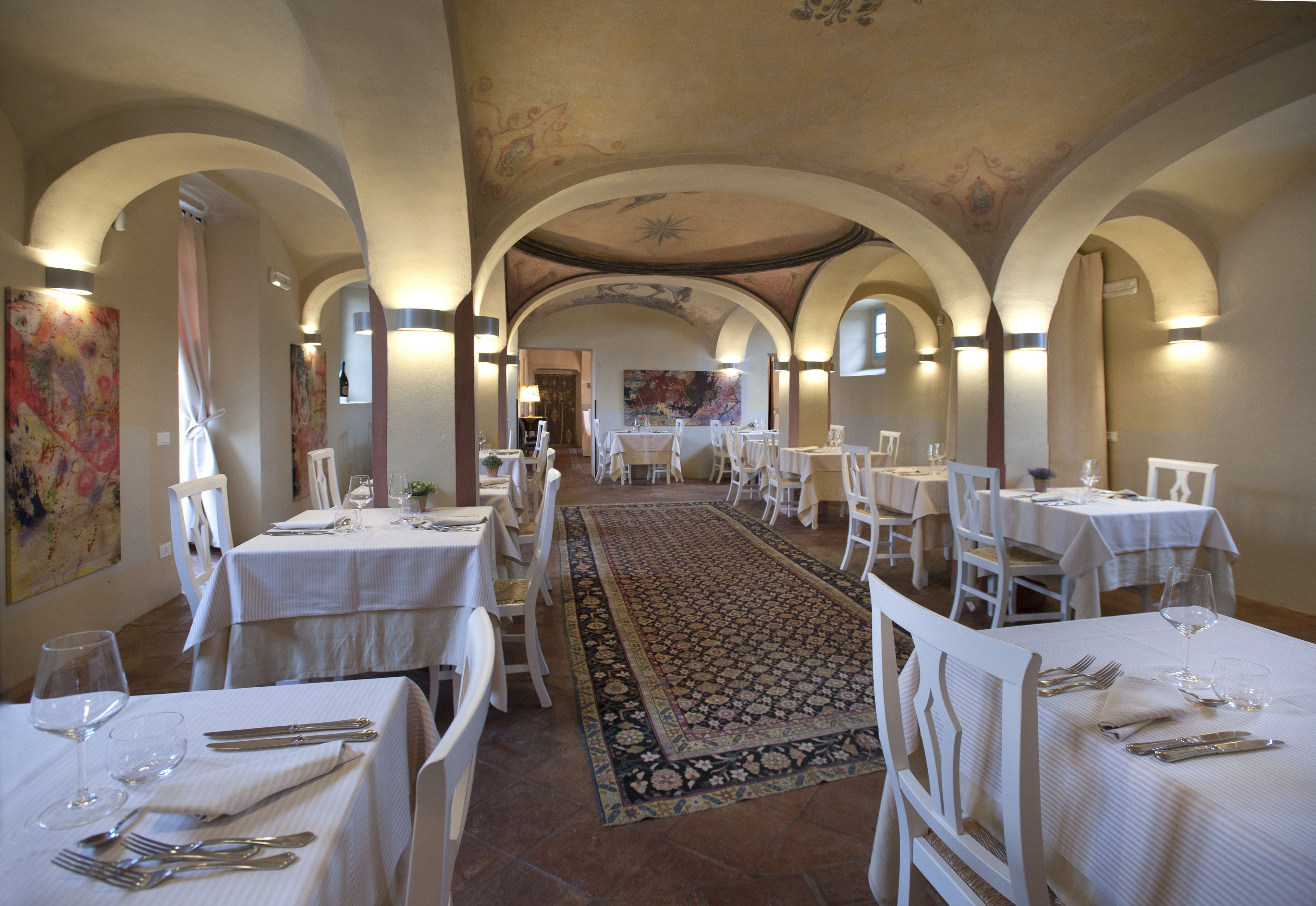 Un restaurante con manteles blancos, sillas blancas y una alfombra estampada.