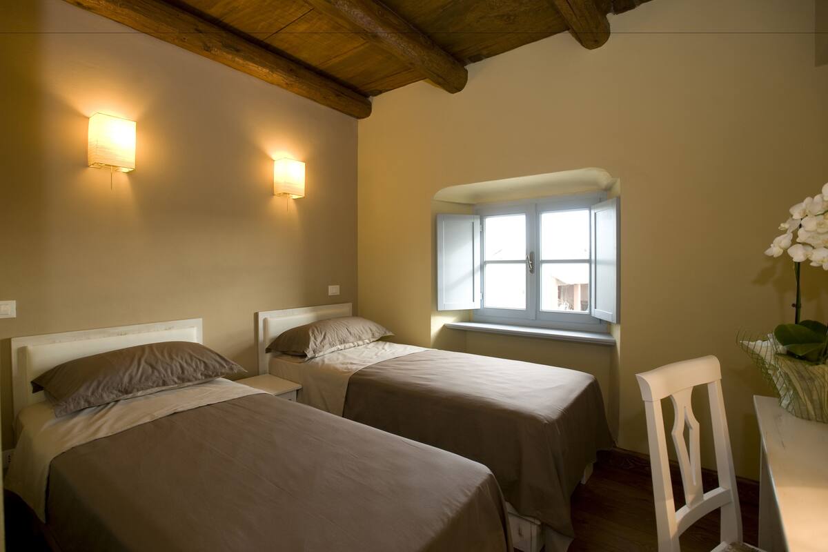 A room with two beds, a window with a view, and a chair.