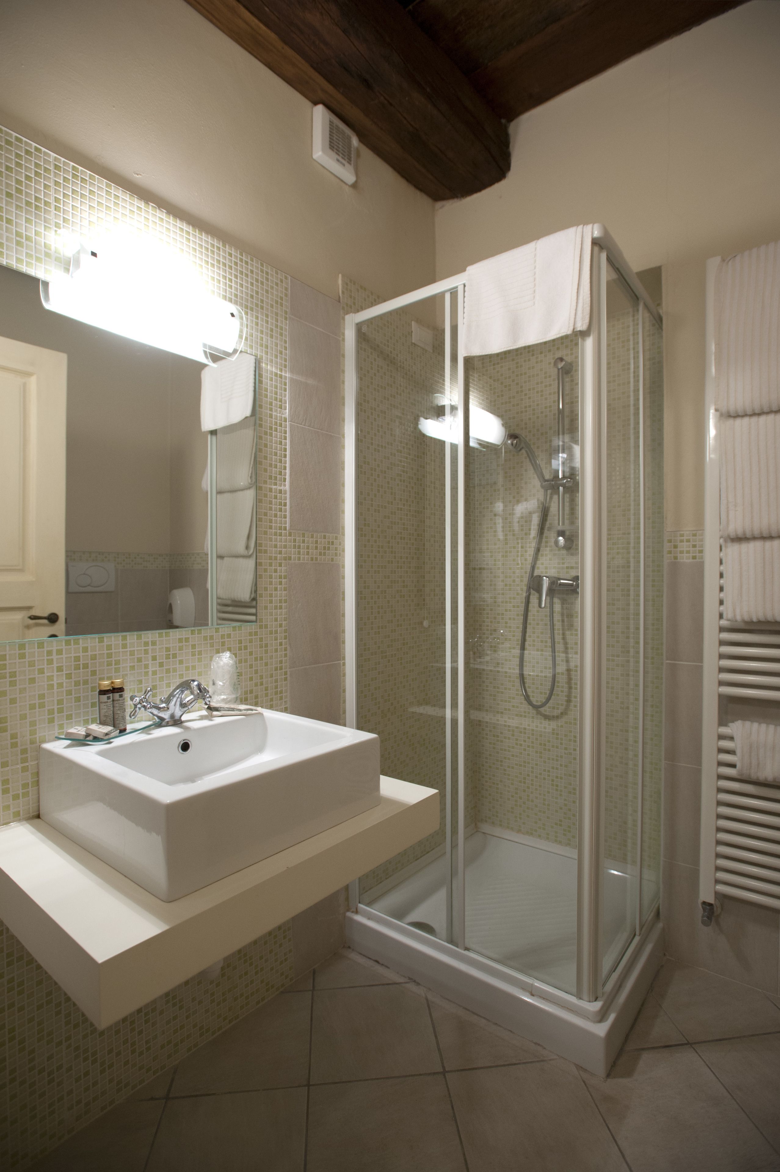 A bathroom with a glass-enclosed shower, a white sink, and a mirror.