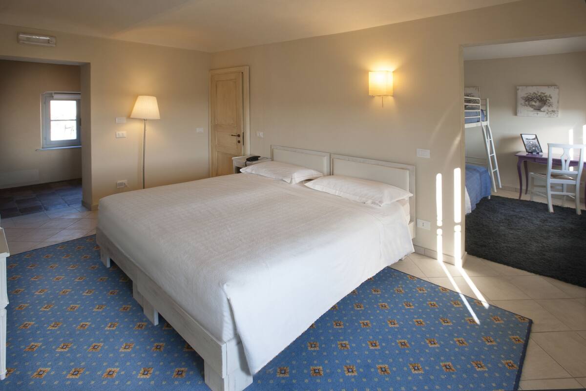 A bedroom with a large bed, a desk, and a chair.