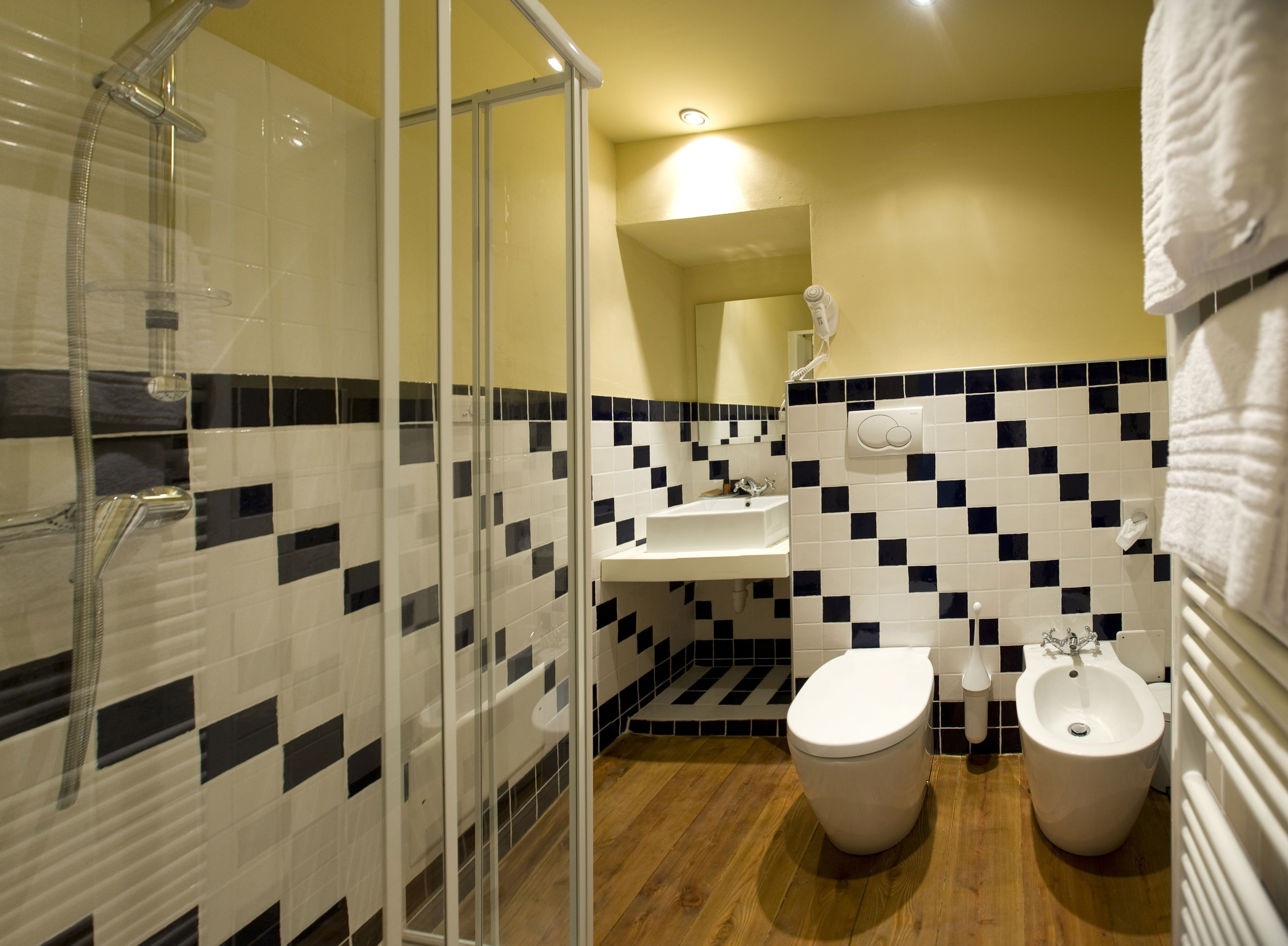 A bathroom with a shower, two toilets, a sink, and a mirror.