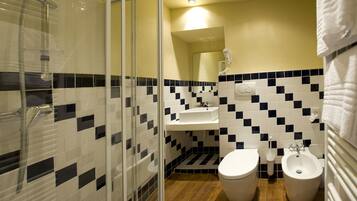 A bathroom with a shower, two toilets, a sink, and a mirror.