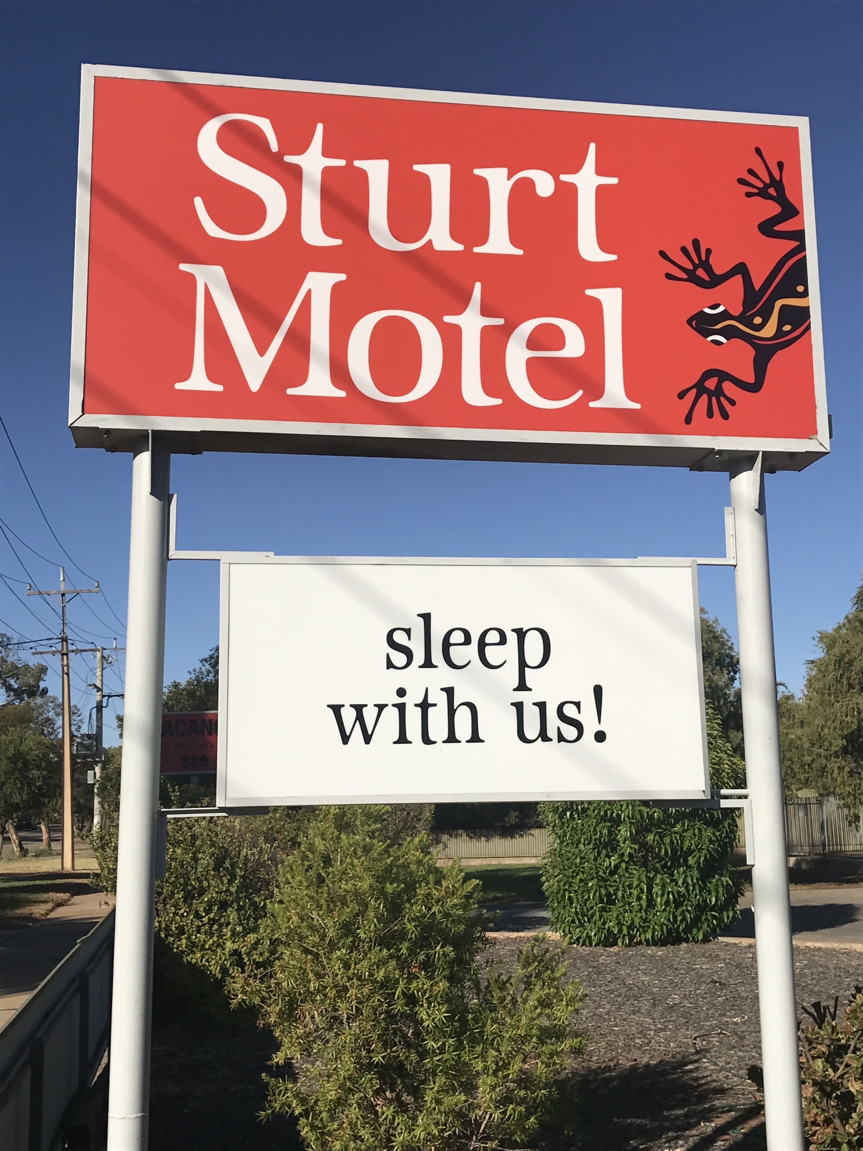 Placa de motel com o nome 'Sturt Motel' e o slogan 'durma conosco!'.