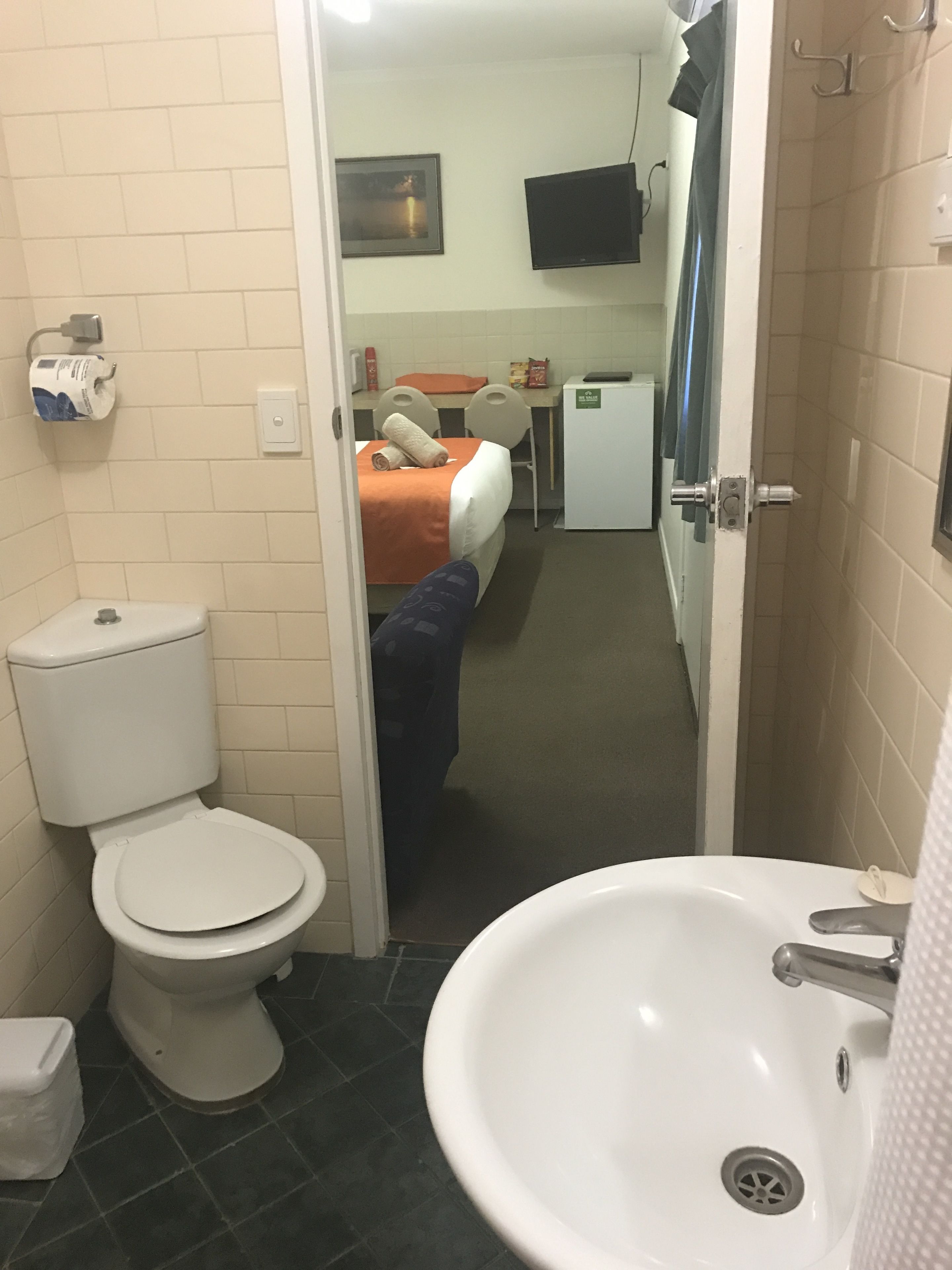 A hotel bathroom with a toilet, sink, and shower.